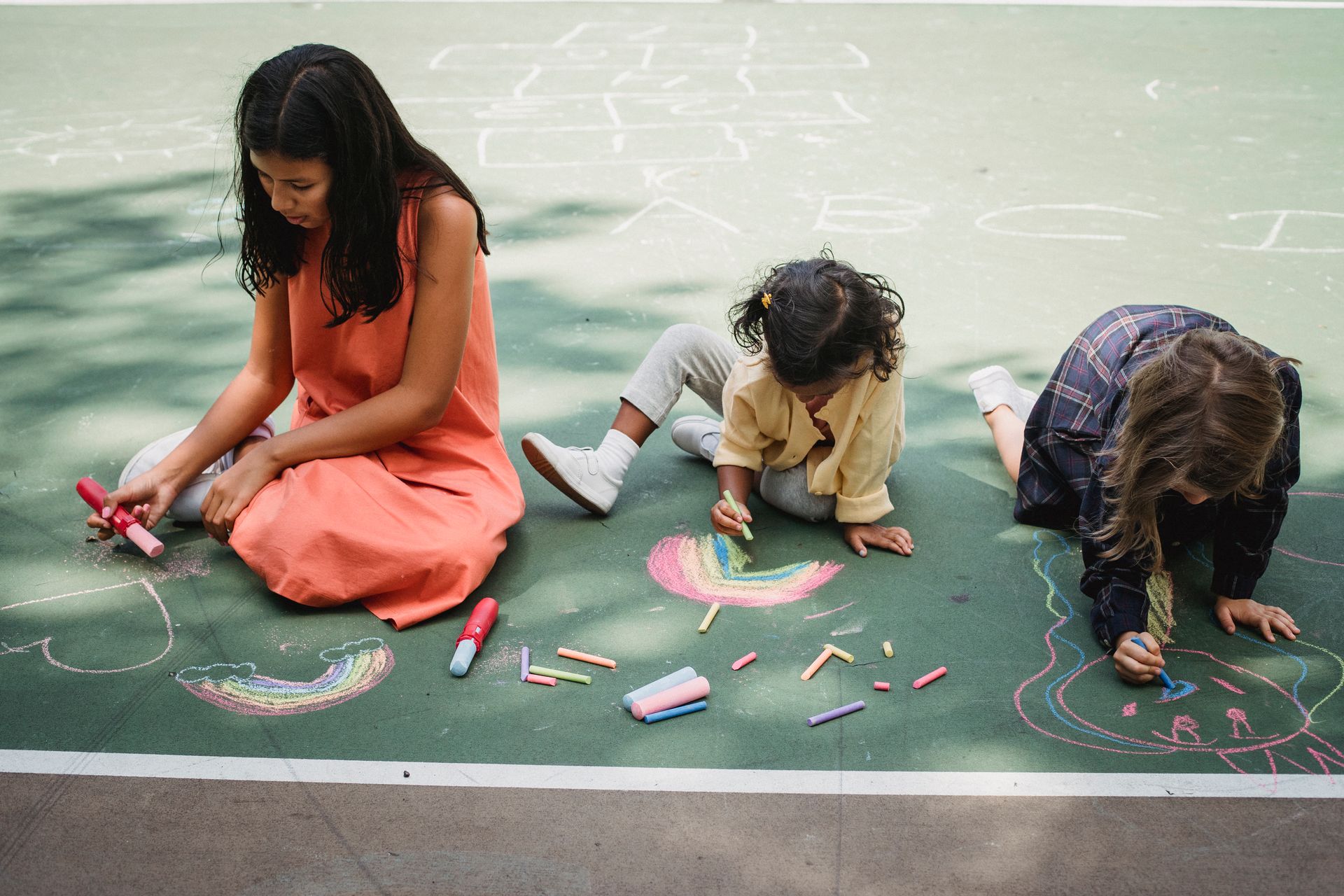 Educator and children creating colourful outdoor artwork